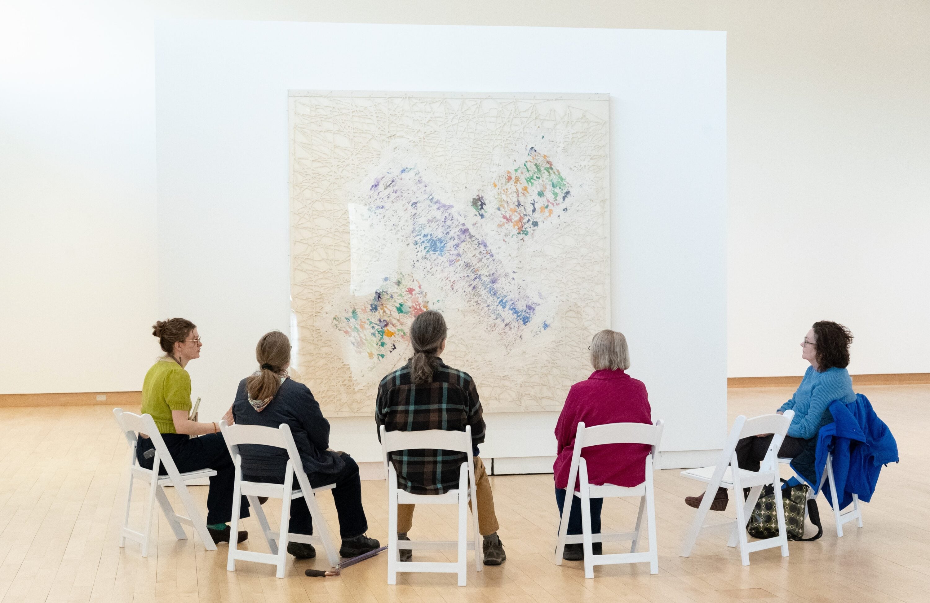 People sitting in front of an artwork in a gallery space.