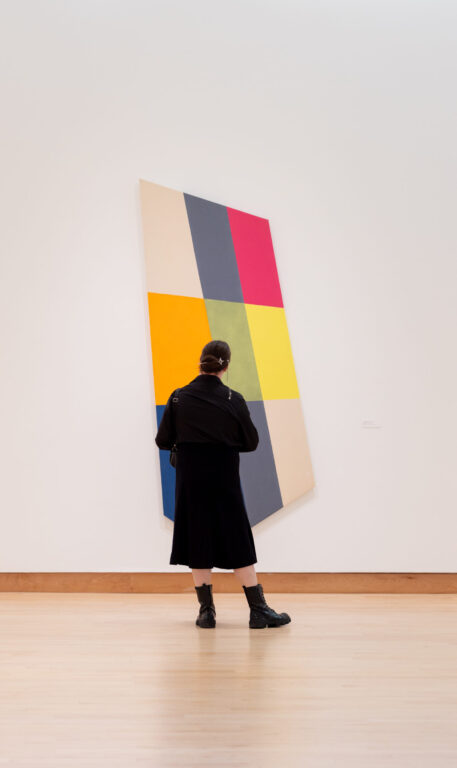 Someone looking at a painting on a slanted canvas.