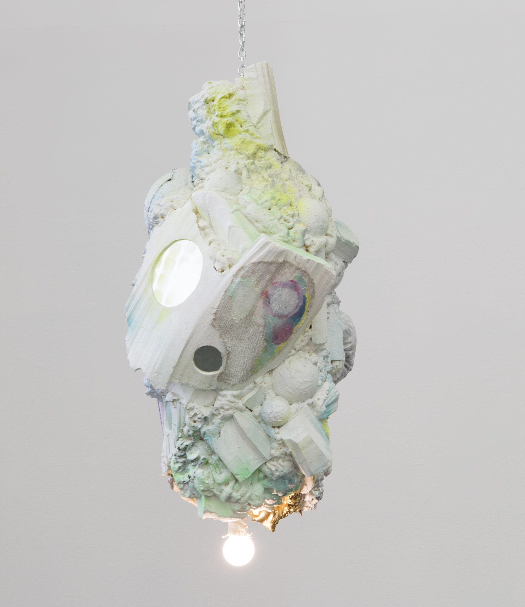 An abstract sculpture with a lightbulb hanging from it.