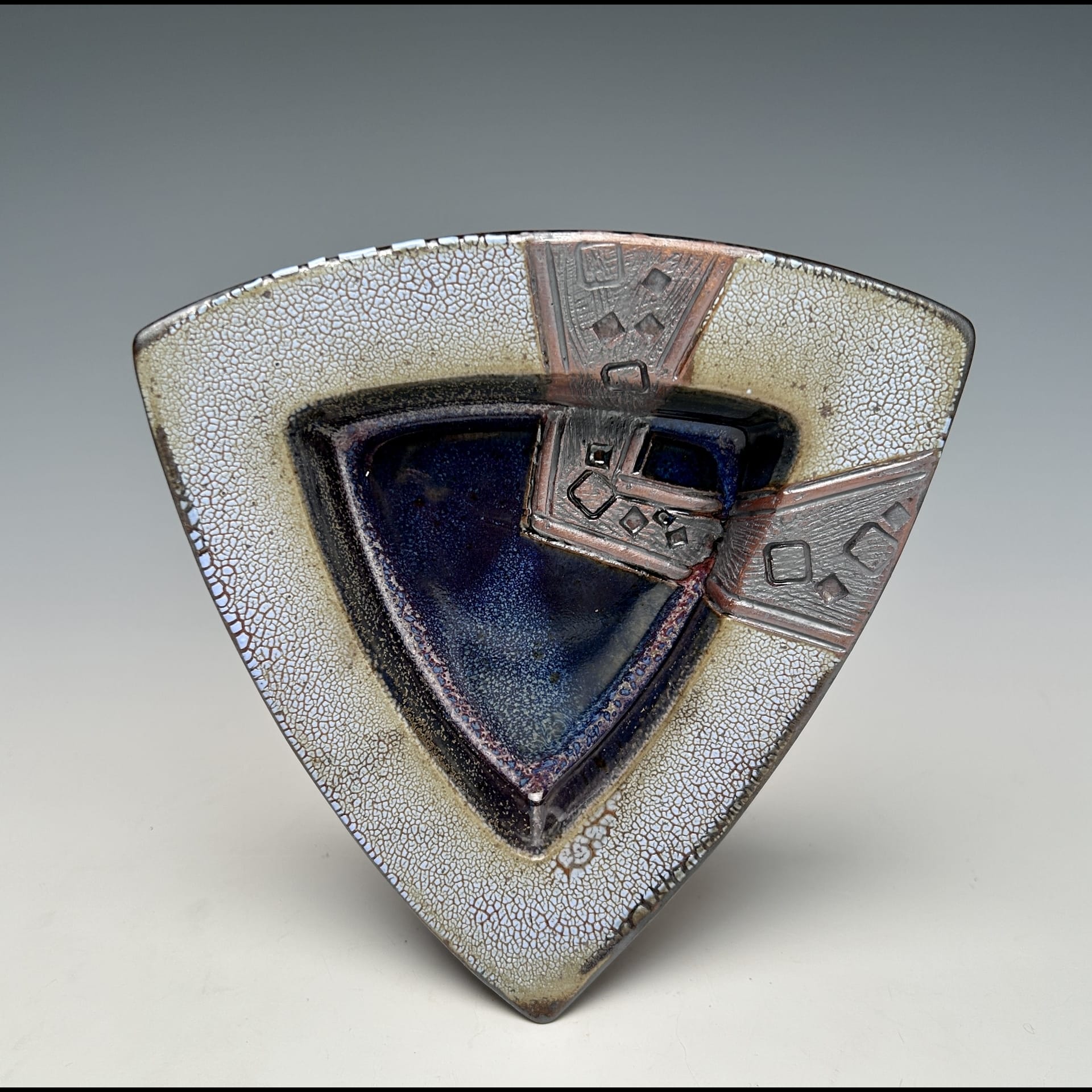 A ceramic triangle with grey and blue.