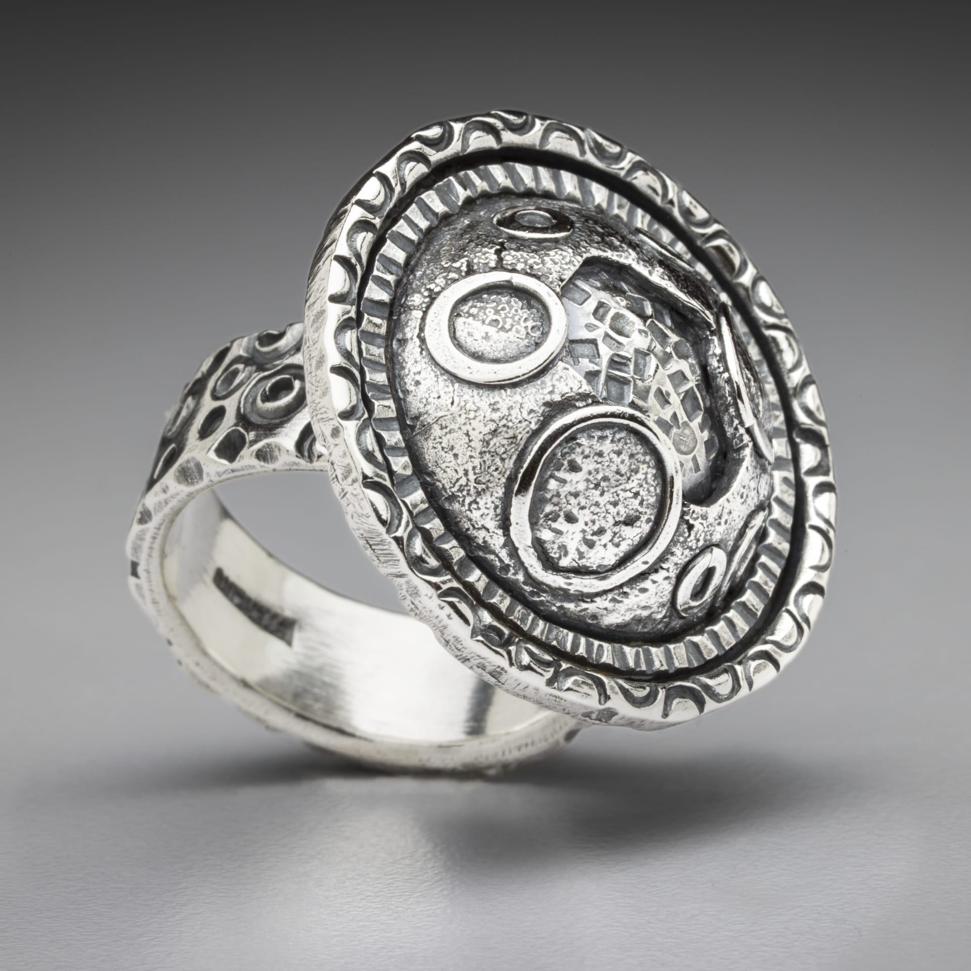 A silver ring with planet like designs.