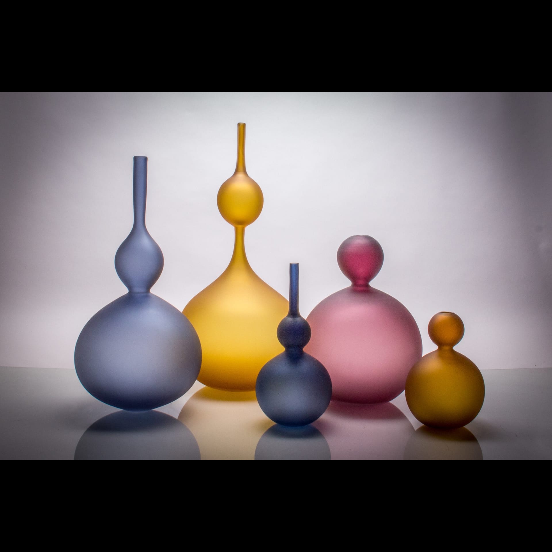Various sized vases that are blue, yellow and pink.