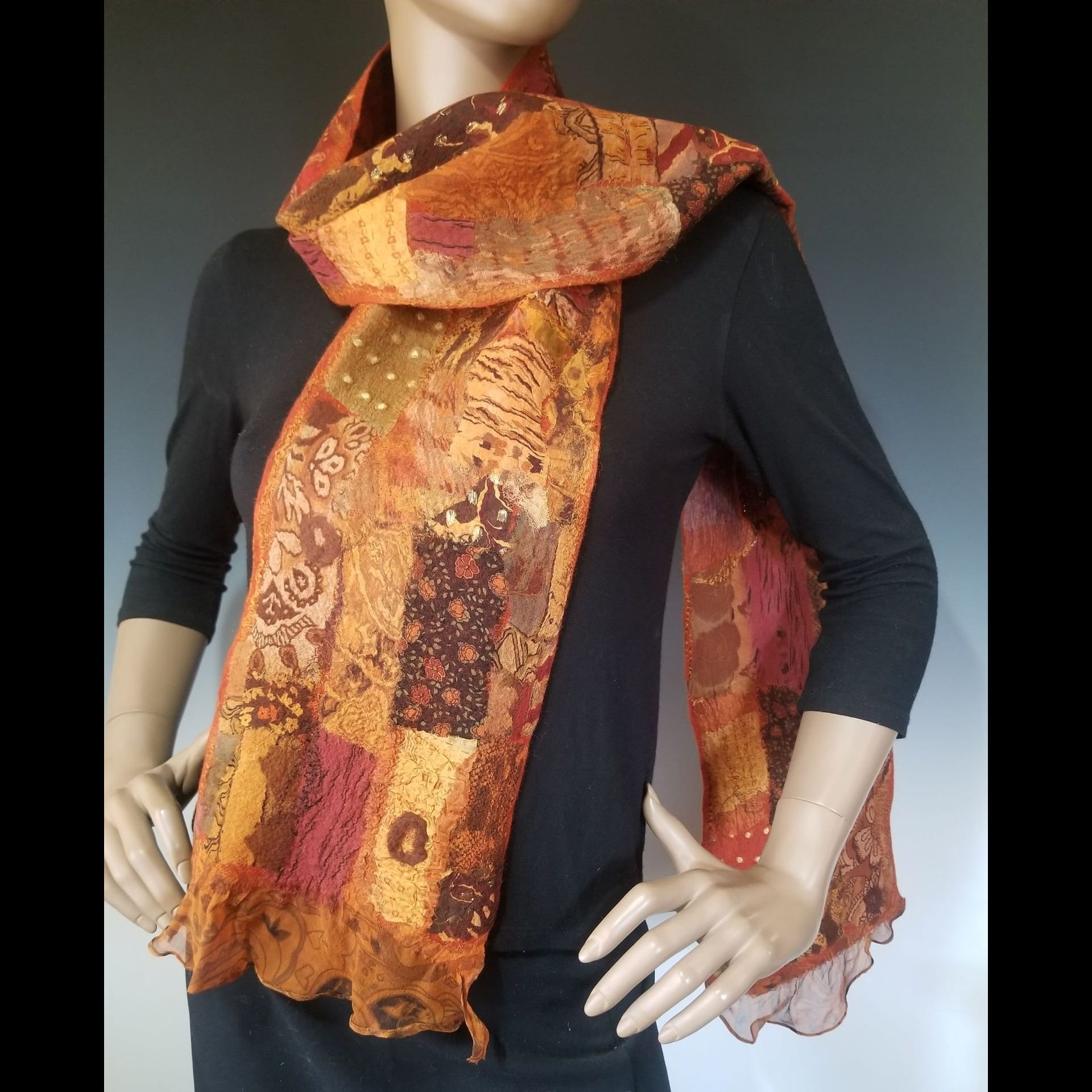 A orange patterned scarf on a mannequin.