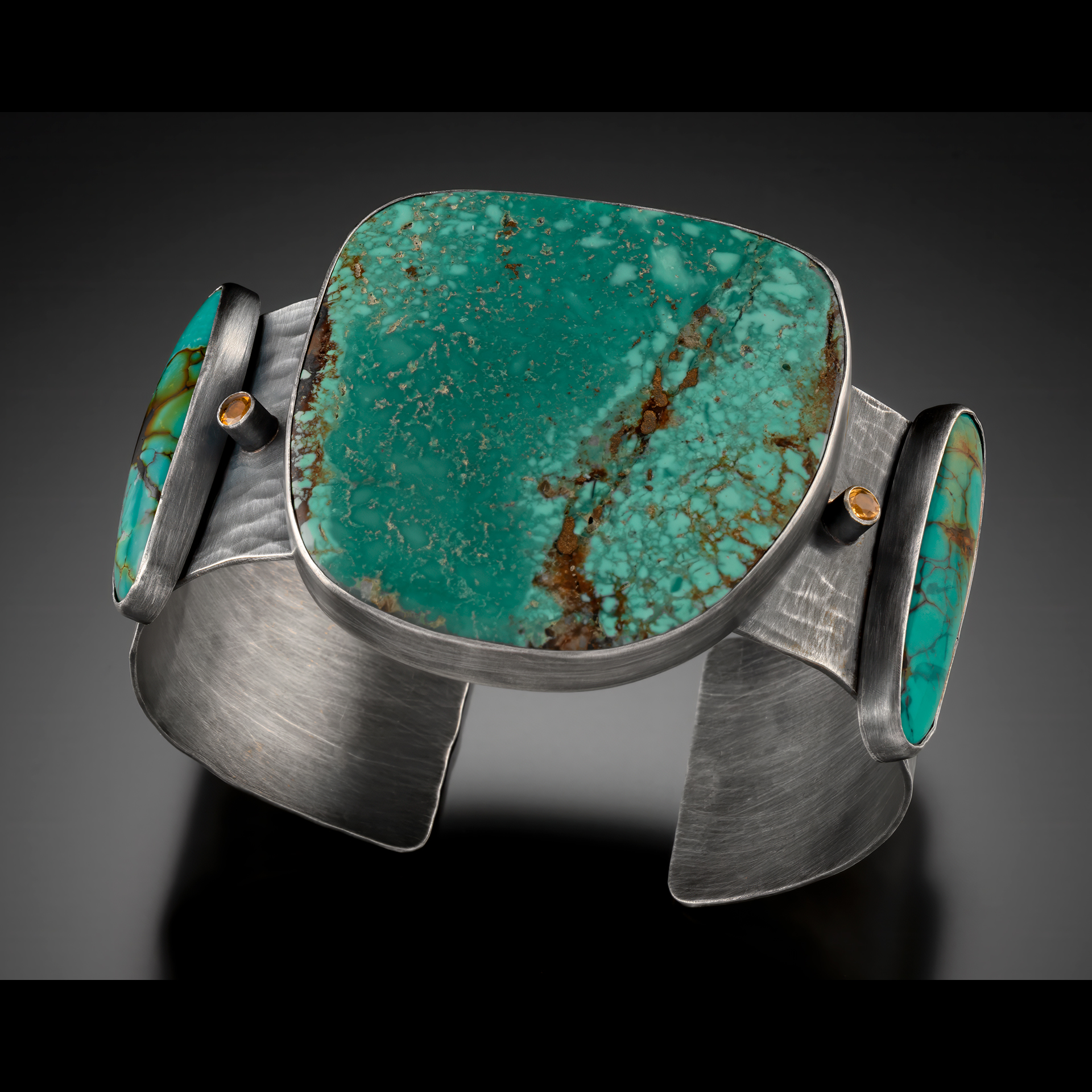 A silver bracelet with teal stones.