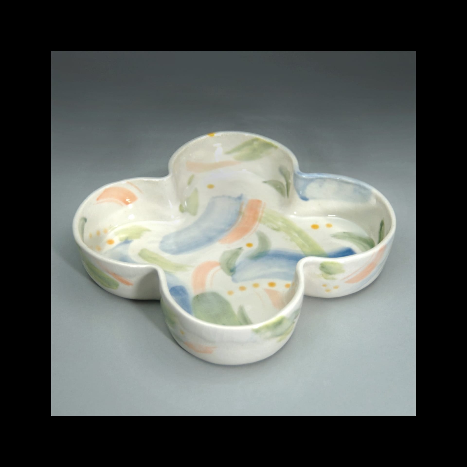 A colorful ceramic dish in the shape of a four leaf clover.