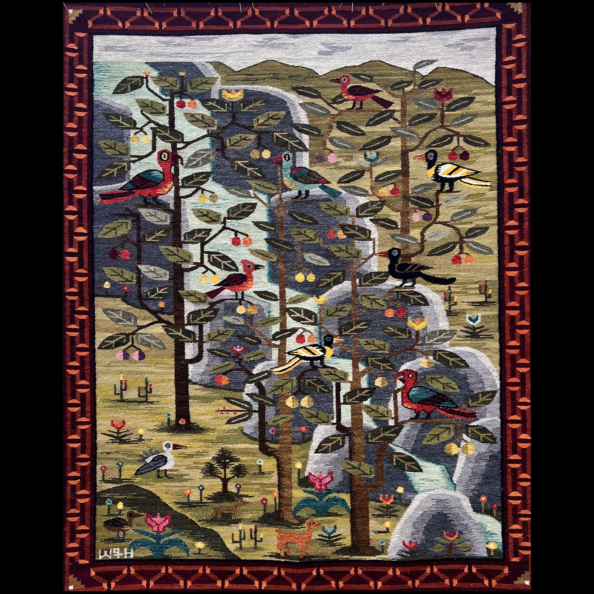 A quilt depicting nature with birds and trees.