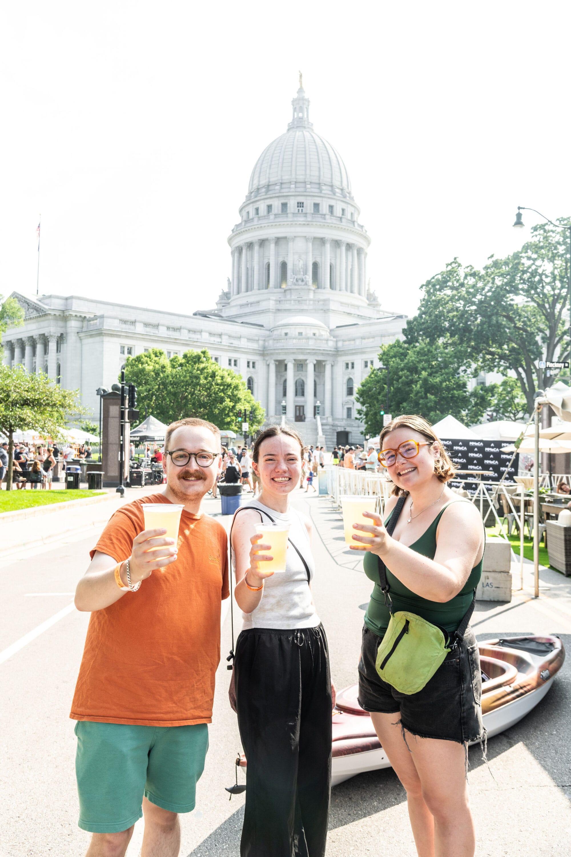 A group of visitors at Art Fair on the Square holding beers with the Capitol Dome in the Background. Muse at Art Fair on the Square. 