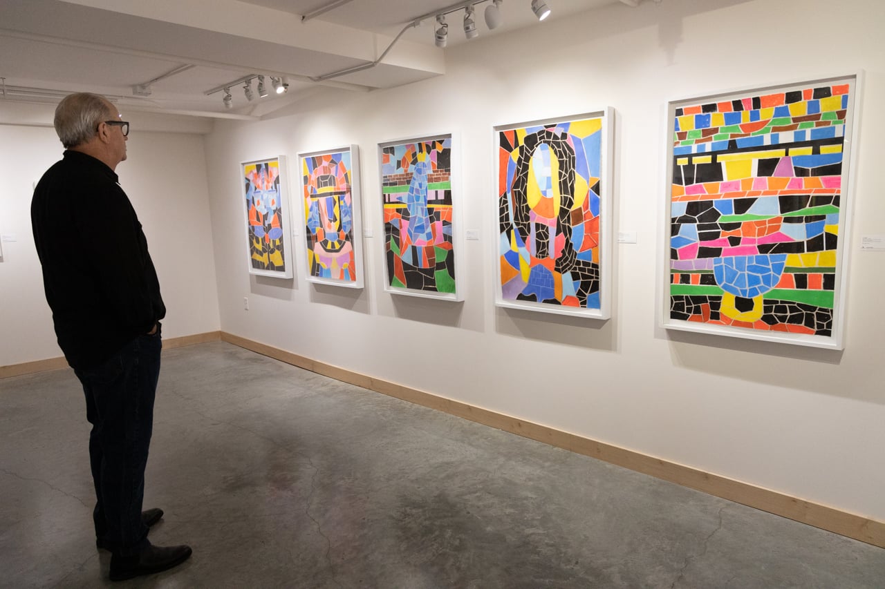 A man looking at colorful artwork in a gallery space.