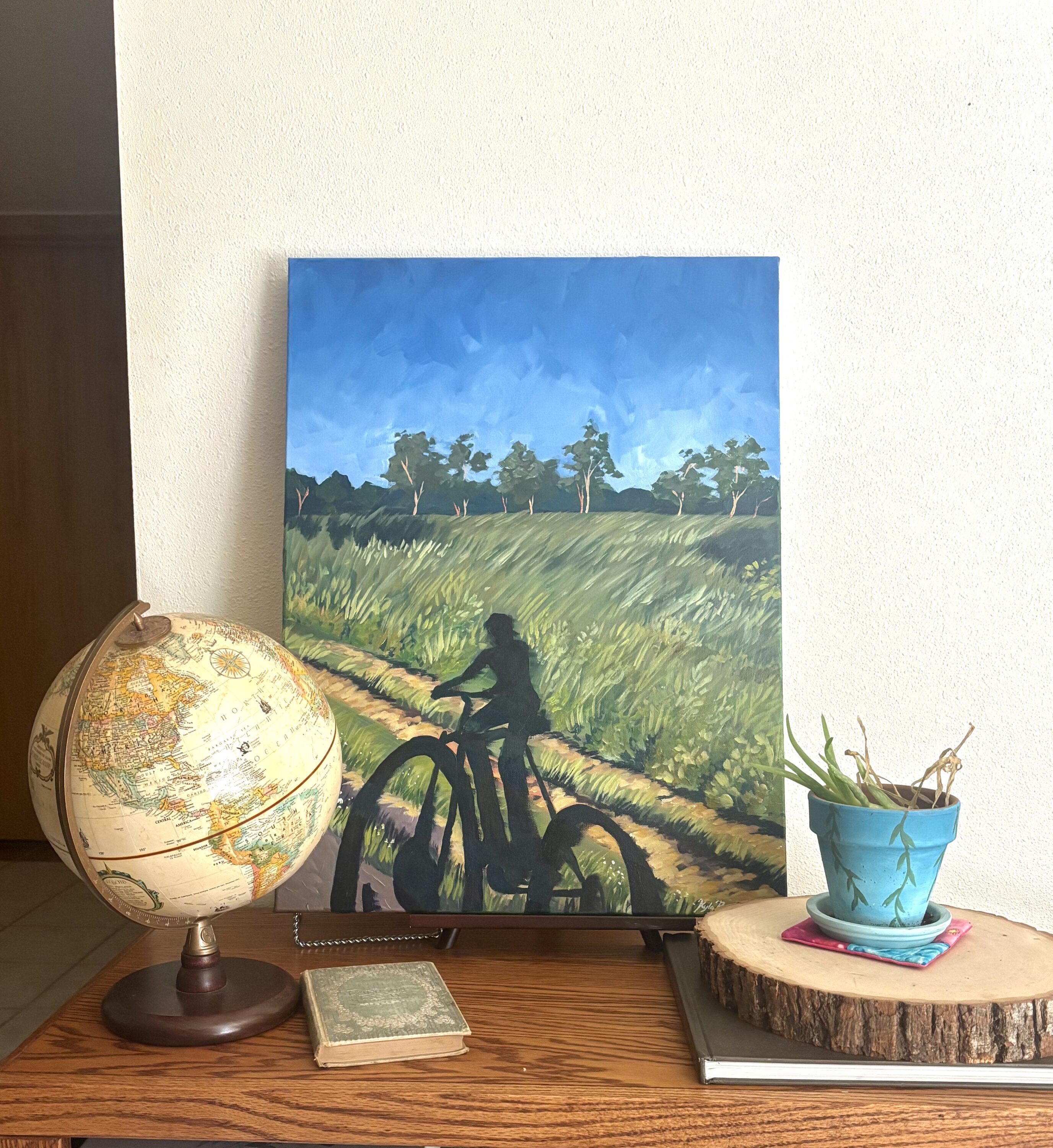 A painting of someone riding a bike next to a globe.