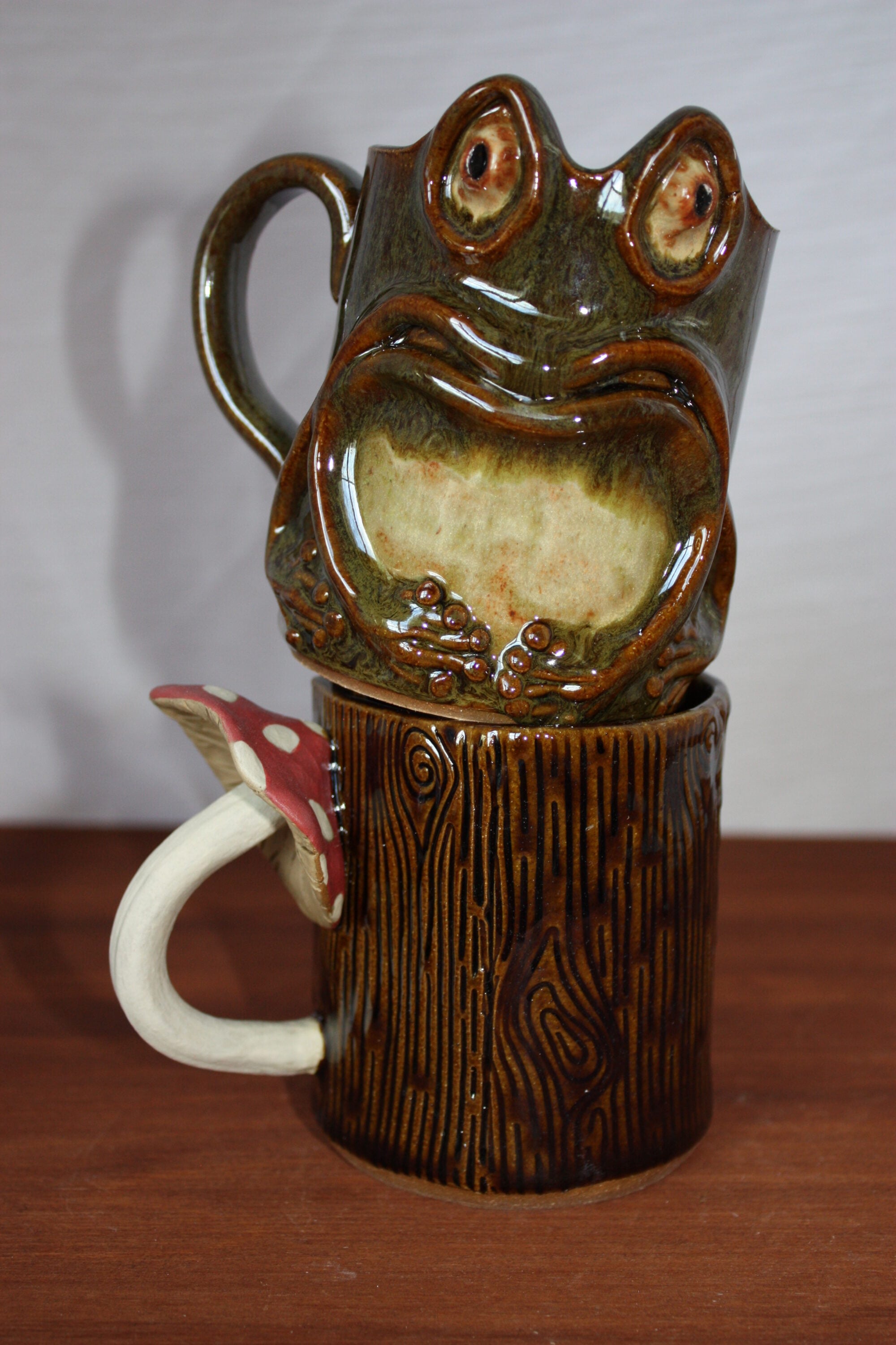 Mugs stacked on top of one another resembling a frog and the other a tree trunk.