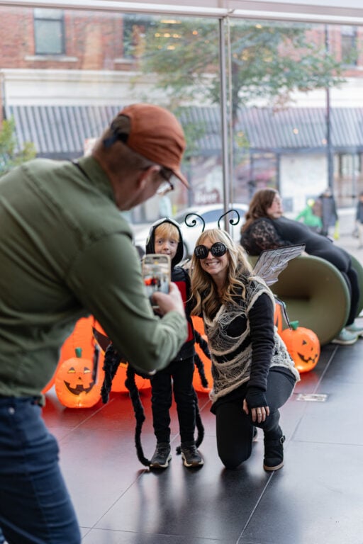 Someone taking a picture of a mom and kid dressed up for Halloween as spiders.