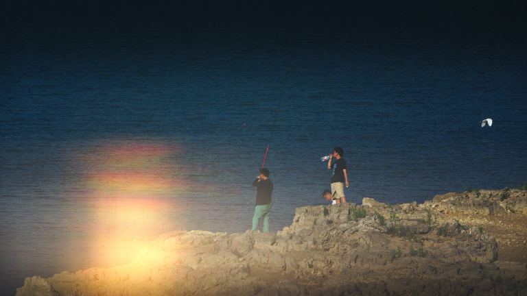 People fishing by a shoreline.