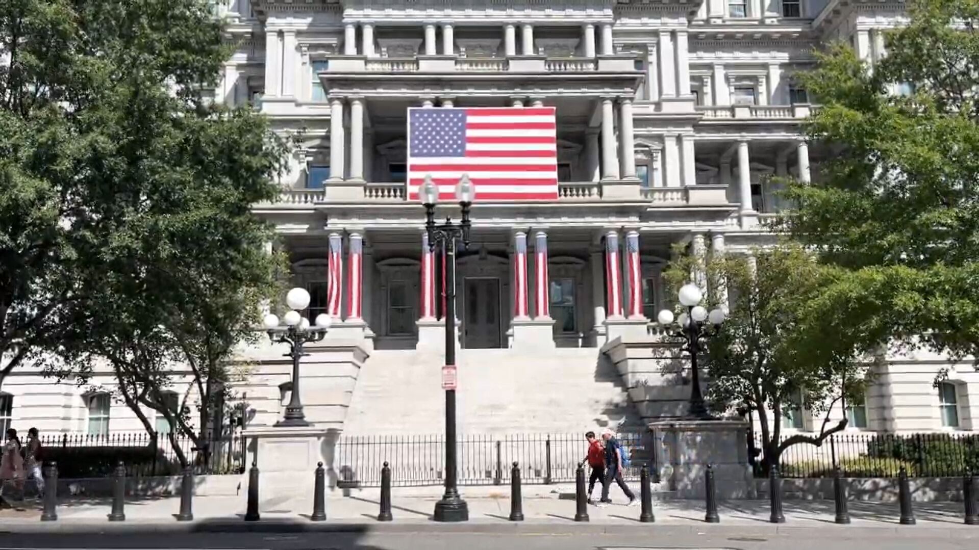 People walking by a building with American flags on it.